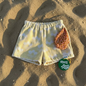 Firefly_Place shorts in reference image flat onto a soft beach sand texture. Late afternoon s 515101